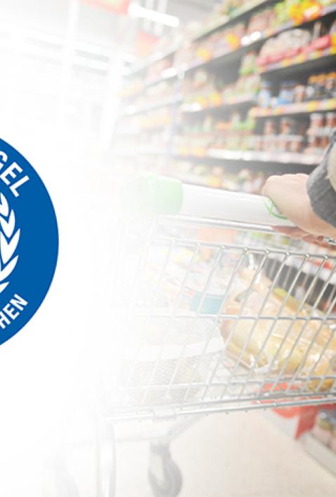 A Shopper Pushes a Trolley along a Supermarket Aisle - Image has a Shallow Depth of Field