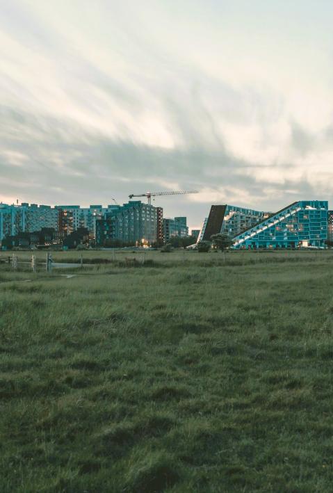 meadows and a bike in the front, urban buildings in the background - Denmark