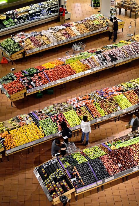 Ein Supermarkt von oben ist mit frischem Obst und Gemüse zu sehen sowie einige Kund*innen