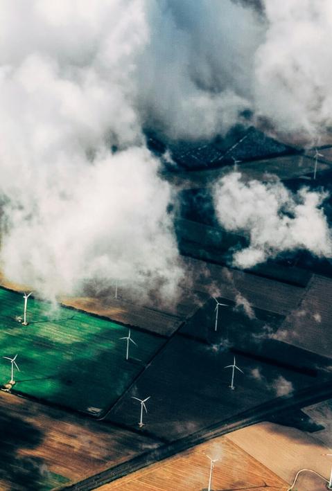 Vogelperspektive auf eine Landschaft mit Windanlagen und Wolken