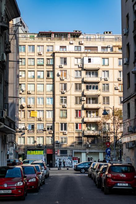 Blick aus einer Straße auf ein älteres mehrstöckiges graues Gebäude  in Bucharest