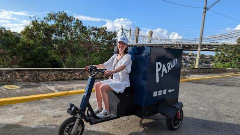 adelphi staff member Johanna sitting on a Parley for the ocean tricycle to collect trash